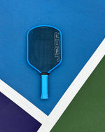 Blue pickleball paddle on a blue and green court
