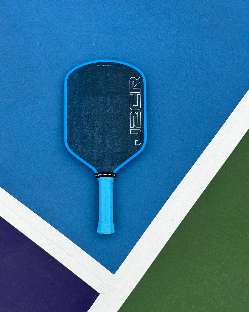 Blue pickleball paddle on a blue and green court